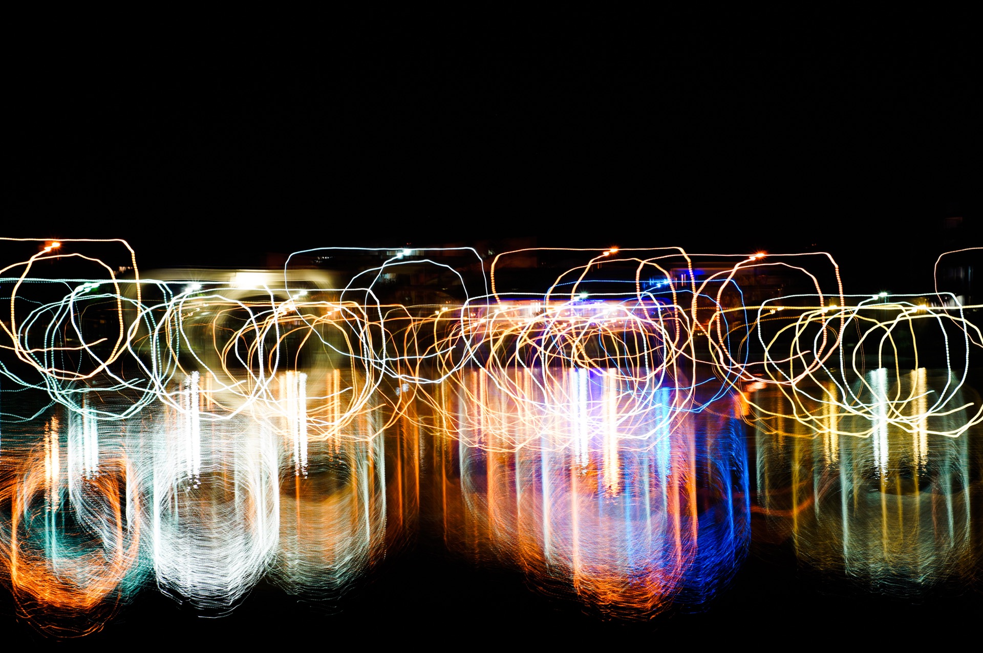 An abstract picture showing spills with their top flattened using light painting technique with vivid mixed rainbow colors on a black background