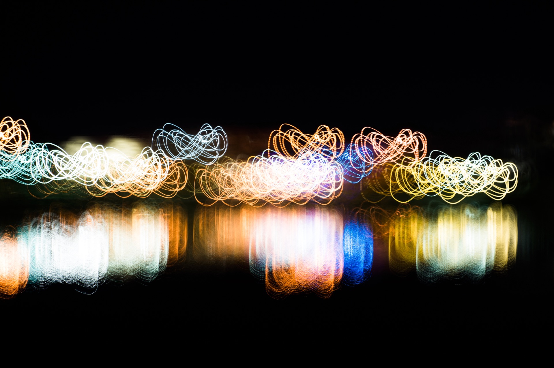 An abstract picture showing eternity loops symbols using light painting technique with vivid mixed rainbow colors on a black background