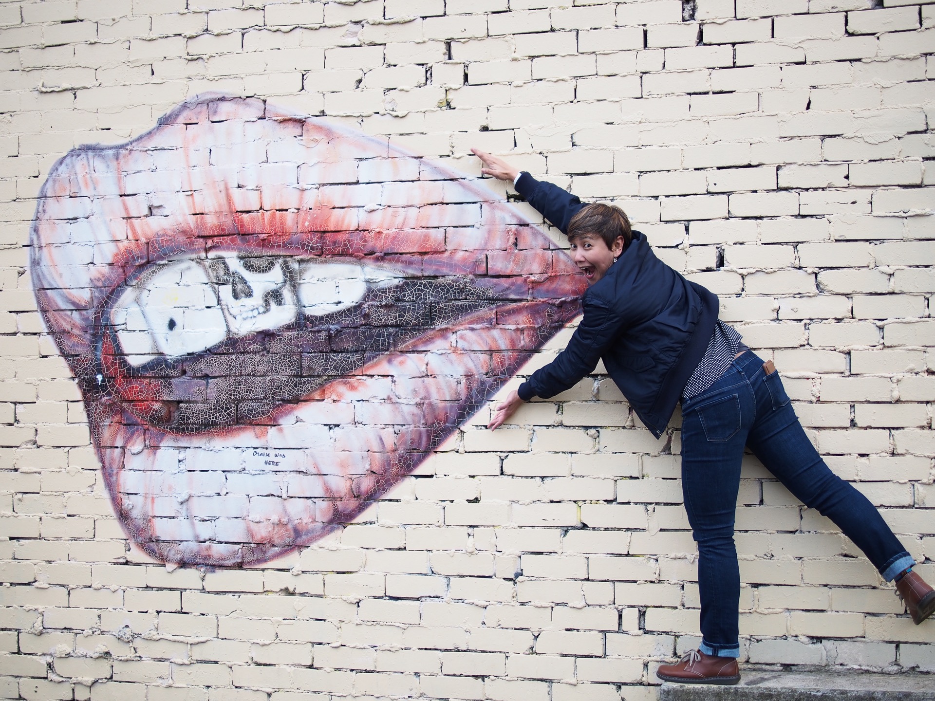 A picture of someone and a piece of street art showing a giant open mouth in Sydney
