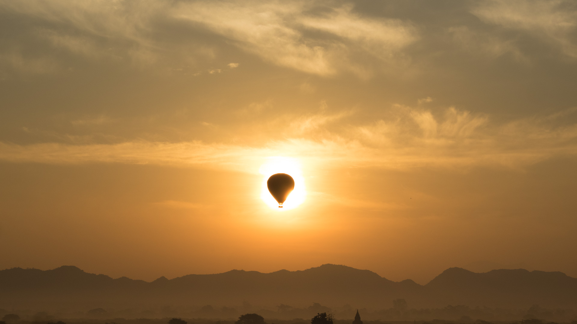 The poetry of a hot air balloon passing across the rising sun.