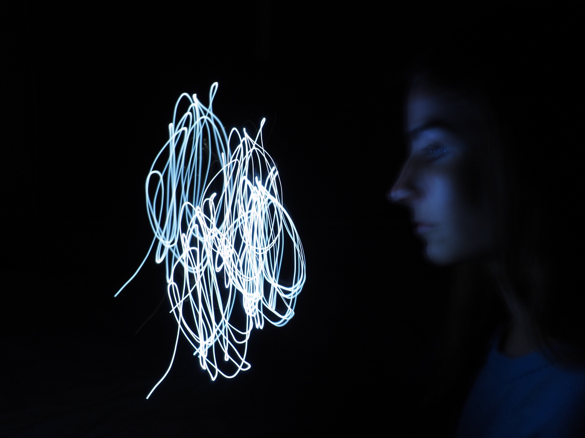 A Self portrait of Erika Degoute Photographer in Sydney showing her looking intensely at a knot of light in a dark room in front of her