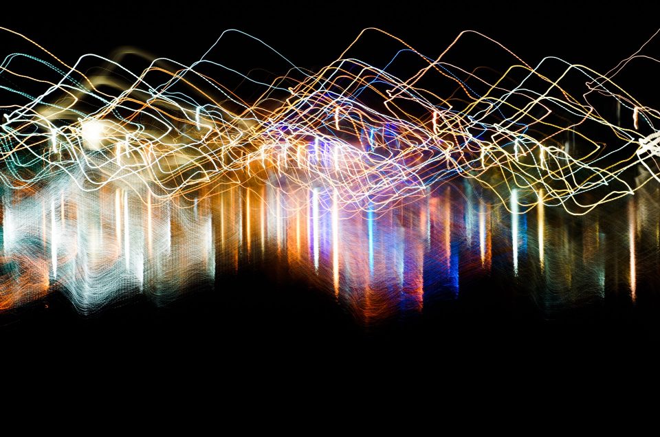 An abstract picture showing large diamond shapes using light painting technique with vivid mixed rainbow colors on a black background